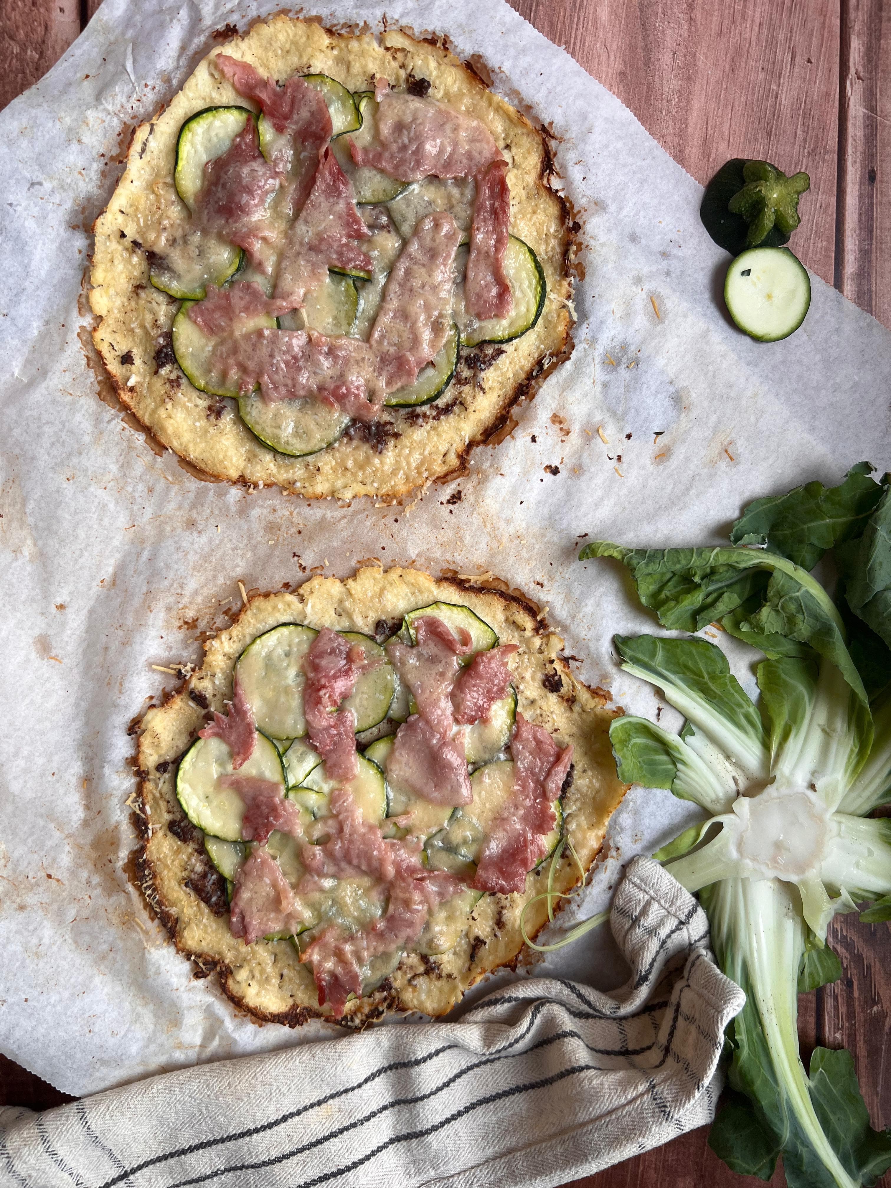 Photo of a tasty cauliflower pizza with zucchini and ham